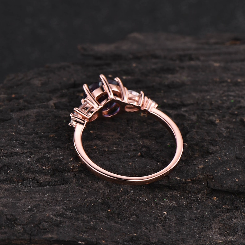Pode incluir: Anel de noivado em ouro rosa com uma grande pedra central oval e pedras de acento menores. O anel &eacute; engastado em uma banda simples.