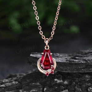 May include: A rose gold necklace with a teardrop-shaped ruby pendant surrounded by smaller ruby and diamond accents.