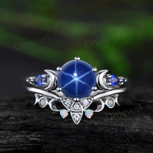 May include: A silver ring set with a large blue star sapphire, two smaller blue sapphires, and two white opals. The ring features a crescent moon design.