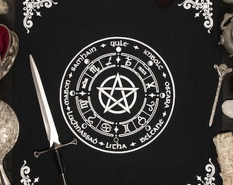 May include: Black altar cloth with a white pentagram and circle with the names of the eight sabbats in a circle around it. The sabbats are: Samhain, Yule, Imbolc, Ostara, Beltane, Litha, Lughnasadh, and Mabon.