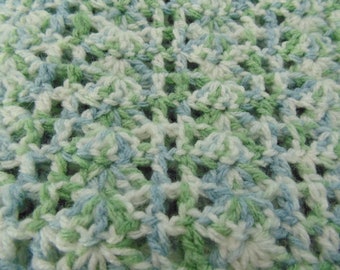 May include: Close-up of a crocheted fabric with a repeating pattern of white, light blue, and green yarn.