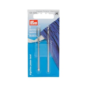 May include: Two silver threading needles with a loop at the top, packaged on a blue and white card with the text "Aiguilles passe-lacet" and "131 320" printed on it.
