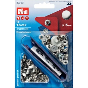 Könnte beinhalten: Eine Packung mit 10 silbernen 'Anorak' Druckknöpfen, auch bekannt als Druckknöpfe, mit einem Durchmesser von 15 mm. Die Packung enthält ein Werkzeug zum Anbringen der Druckknöpfe.