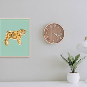 May include: A framed print of a tiger on a light green background. The tiger is facing right and has orange and black stripes. The frame is light wood.