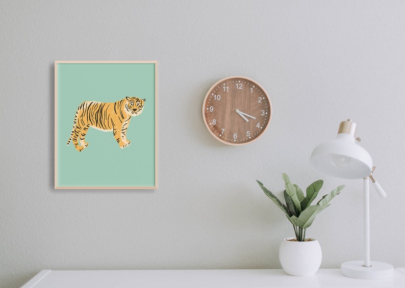 May include: A framed print of a tiger on a light green background. The tiger is facing right and has orange and black stripes. The frame is light wood.