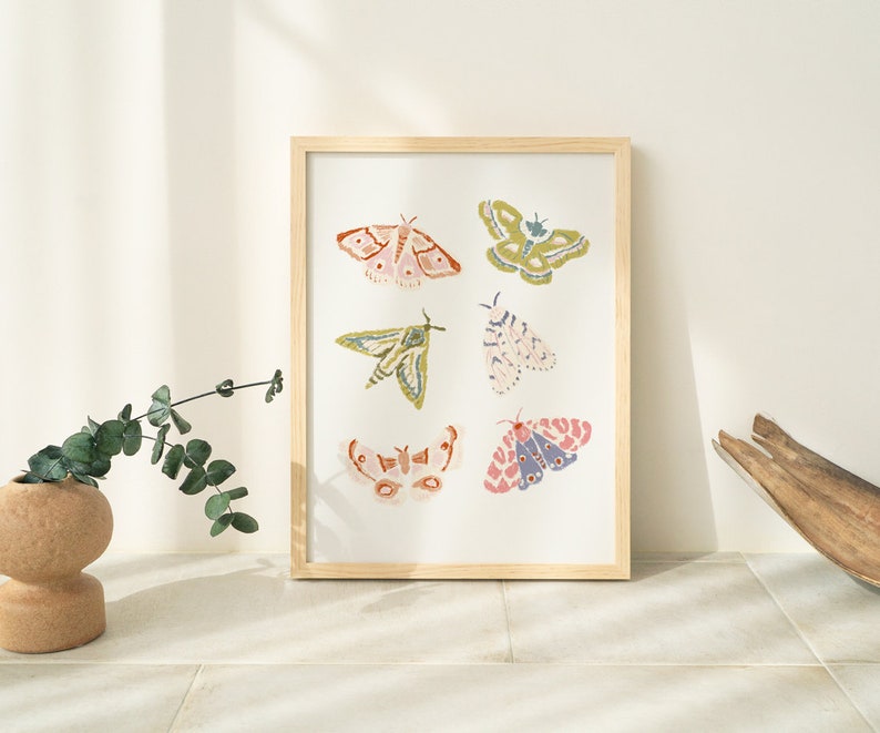 Puede incluir: Una impresi&oacute;n enmarcada con seis ilustraciones coloridas de polillas con detalles intrincados. Las polillas se representan en varias poses y colores, incluyendo rosa, verde, azul y amarillo.