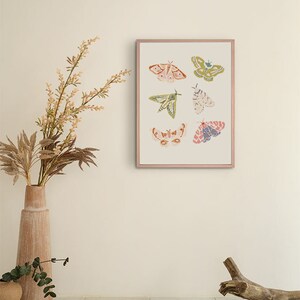 Puede incluir: Una impresi&oacute;n enmarcada con fondo blanco que presenta seis mariposas coloridas con intrincados patrones. Las mariposas est&aacute;n dispuestas en un patr&oacute;n sim&eacute;trico con una combinaci&oacute;n de colores rosa, verde y azul.