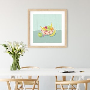 May include: A framed illustration of a bowl of fruit on a light blue background. The bowl is filled with bananas, apples, and oranges. The bowl is red and white with a striped pattern.