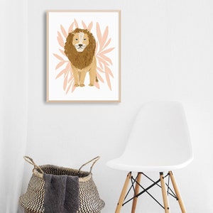May include: A framed art print featuring a lion illustration. The lion is depicted in shades of brown and tan, set against a backdrop of pink leaf-like shapes. The artwork is in a light wooden frame, suitable for nursery or home decor.