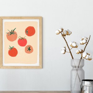 Op de afbeelding: Een ingelijst afdruk van een minimalistische illustratie van rode tomaten op een perzikkleurige achtergrond. De afdruk is in een licht houten frame.