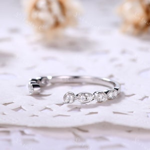 May include: A silver-toned open band ring featuring a series of alternating round and marquise-shaped clear stones set along the top. The metal band has a polished finish, and the stones are secured in individual settings with milgrain detailing.