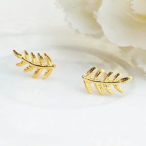 May include: A pair of gold leaf earrings. The earrings are small and delicate, with a simple design. They are perfect for everyday wear.