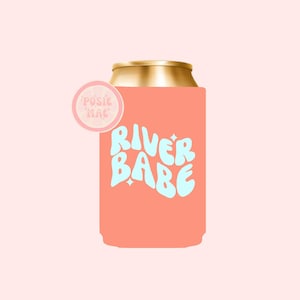 May include: A pink can cooler with a gold top and the text "River Babe" in a light blue font. A small pink circle with the text "Possie Mae" is on the side.