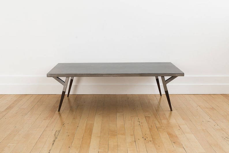 May include: A rectangular, gray concrete coffee table with a metal frame and dark brown legs.
