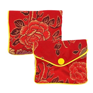 May include: Two red fabric pouches with floral patterns and yellow trim. The pouch on the right has a yellow button.