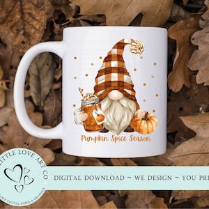 May include: White ceramic mug with a gnome design, wearing a plaid hat and holding a pumpkin spice latte and a pumpkin. The mug has the text "Pumpkin Spice Season" and "The Little Love Art Co."