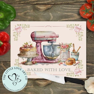 May include: A pink and white kitchen chopping board with a watercolour illustration of a stand mixer, cake, and other baking supplies. The text "Baked with Love" is printed on the board. The board is surrounded by a floral border.