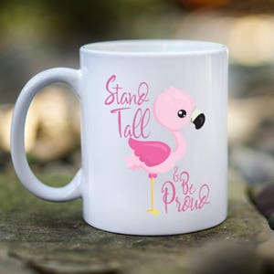 May include: White ceramic mug with a pink flamingo illustration and the text "Stand Tall & Be Proud".