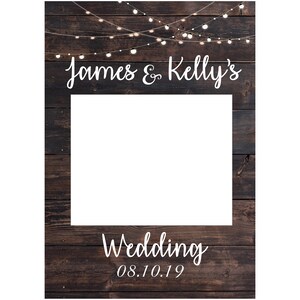 May include: A rustic wooden photo booth backdrop with string lights and the text "James & Kelly's Wedding 08.10.19".