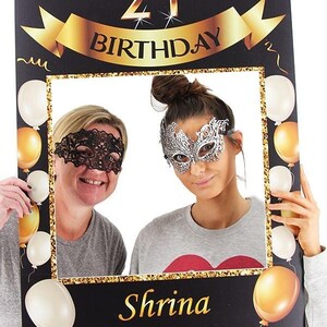 May include: Black photo booth prop with gold glitter trim and balloons. The top of the prop says "21st Birthday" with a gold ribbon. The bottom of the prop says "Shrina 03.10.2019".