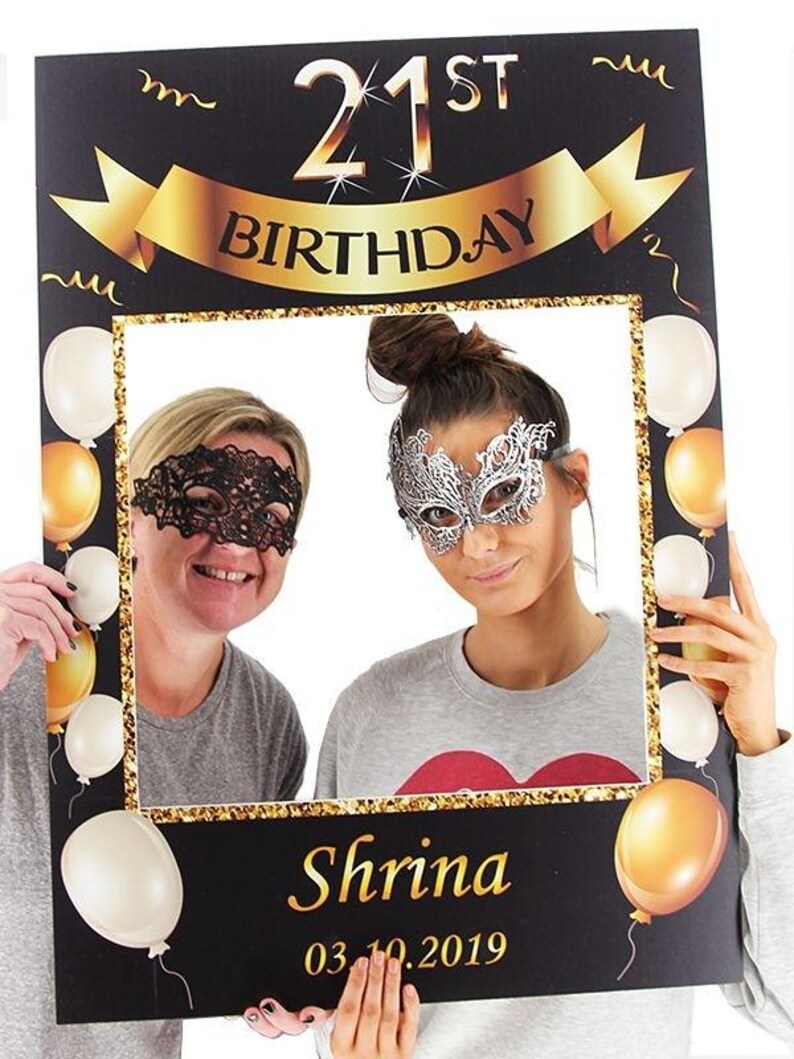 May include: Black photo booth prop with gold glitter trim and balloons. The top of the prop says "21st Birthday" with a gold ribbon. The bottom of the prop says "Shrina 03.10.2019".