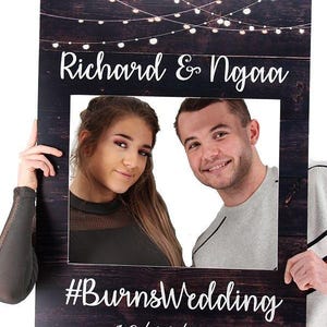May include: A rustic wooden photo booth prop with string lights, a white frame, and the text "Richard & Ngaoa #BurnsWedding 10/10/2019".