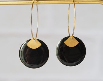 May include: A pair of gold hoop earrings with black circular pendants. Each pendant has a smaller gold crescent shape on top.