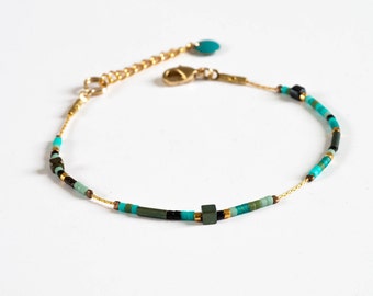 Puede incluir: Un delicado brazalete de cadena dorada con cuentas turquesa, verdes y negras. El brazalete tiene un cierre de mosquetón.