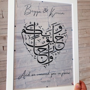 Könnte beinhalten: Ein weißer gerahmter Druck mit schwarzer Kalligraphie in Form eines Herzens. Der Text lautet "Beyza & Kerim" und "Und wir haben euch in Paaren erschaffen, Koran 78:8".