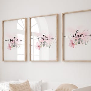 May include: Three framed prints with pink watercolor floral designs and the words "sabur", "shukir", and "dua" in black calligraphy.