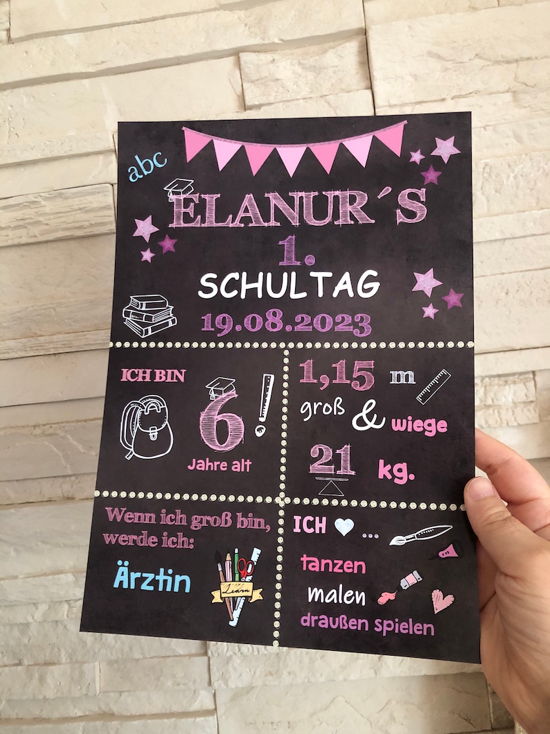 Puede incluir: Un cartel de pizarra con decoraciones rosas y blancas que anuncia el primer d&iacute;a de escuela de un ni&ntilde;o. El cartel incluye el nombre del ni&ntilde;o, "ELANUR'S", la fecha "19.08.2023", y la edad y la altura del ni&ntilde;o. El cartel tambi&eacute;n incluye una lista de cosas que al ni&ntilde;o le gusta hacer, como bailar, pintar y jugar al aire libre.