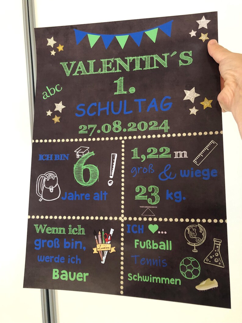 Puede incluir: Un cartel de pizarra con el texto "Valentin's 1. Schultag 27.08.2024" en letras azules y verdes. El cartel tambi&eacute;n incluye informaci&oacute;n sobre la edad, la altura y el peso de Valentin, as&iacute; como sus intereses, que incluyen f&uacute;tbol, tenis y nataci&oacute;n.