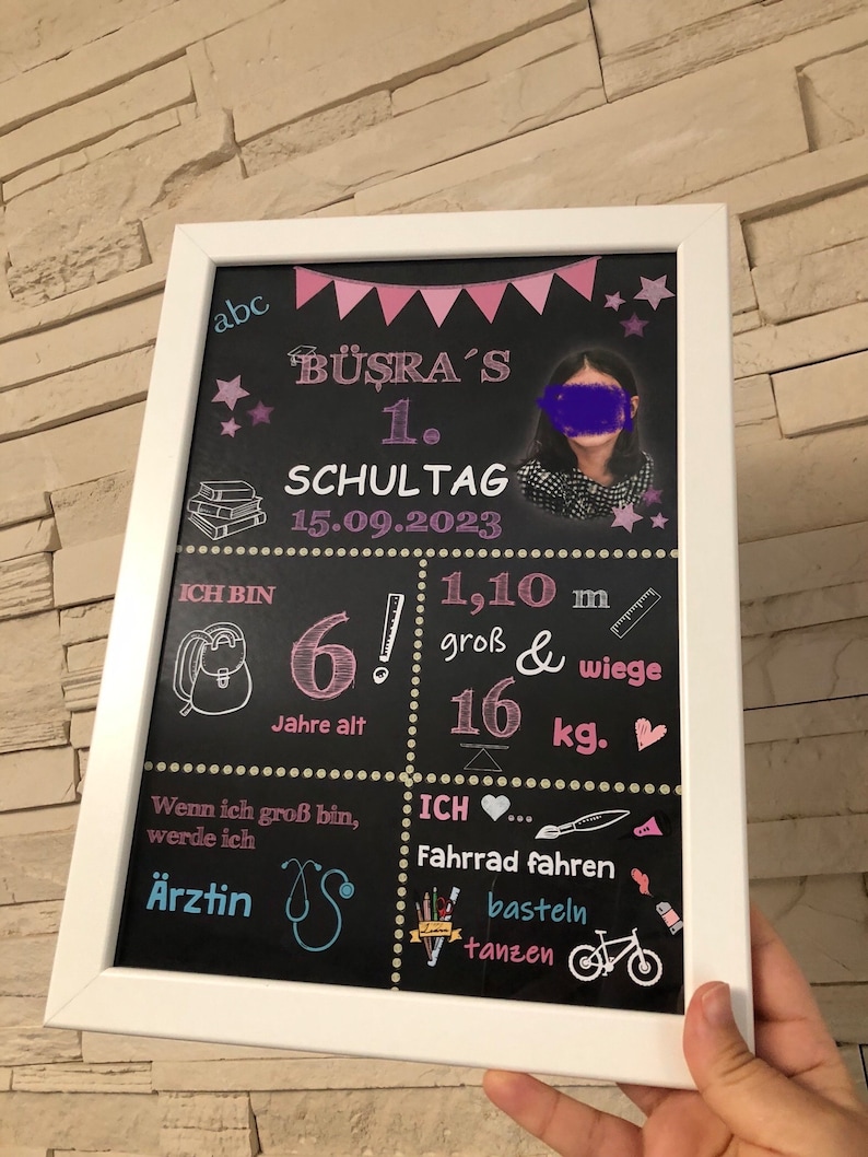 Puede incluir: Una pizarra negra con marco blanco, decorada con estrellas, banderas y corazones rosas y blancos. La pizarra tiene el texto "B&Uuml;ŞRA'S 1. SCHULTAG 15.09.2023" y una foto de una ni&ntilde;a. Tambi&eacute;n incluye el texto "ICH BIN 6! Jahre alt 1,10 m gro&szlig; & wiege 16 kg." y "Wenn ich gro&szlig; bin, werde ich &Auml;rztin."  La pizarra tambi&eacute;n incluye el texto "ICH... Fahrrad fahren basteln tanzen".