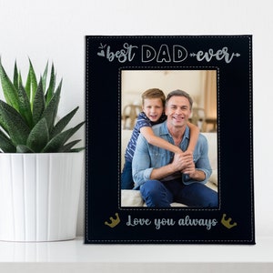 May include: Black photo frame with a stitched border and the text "best DAD ever" and "Love you always" with gold crowns. A photo of a father and son is in the frame.