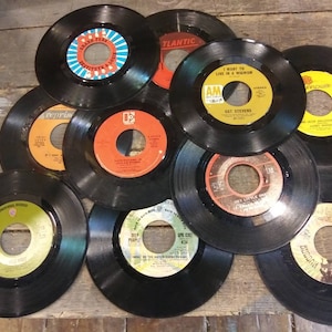 May include: A collection of ten vintage vinyl records with various artists and song titles. The records are black with yellow, red, and blue labels.