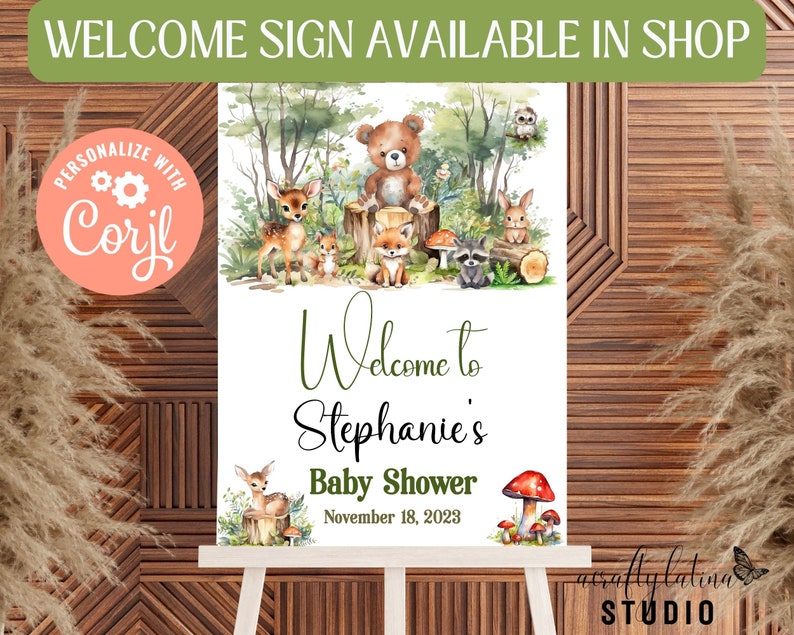 May include: A welcome sign for a baby shower with a woodland theme. The sign features a watercolour illustration of a bear, deer, fox, raccoon and owl in a forest setting. The text on the sign reads "Welcome to Stephanie's Baby Shower November 18, 2023".