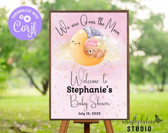 Puede incluir: Un cartel de baby shower rosa y dorado con una luna de dibujos animados y un oso durmiendo sobre ella. El cartel dice "We are Over the Moon" y "Welcome to Stephanie's Baby Shower" con la fecha "July 15, 2023".