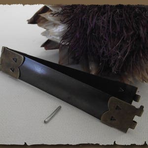 Può includere: Pinze in metallo marrone scuro con accenti color ottone e un piccolo perno in metallo argentato. Le pinze sono aperte e sullo sfondo c'è una composizione di fiori secchi. Le pinze hanno un design decorativo alle estremità.