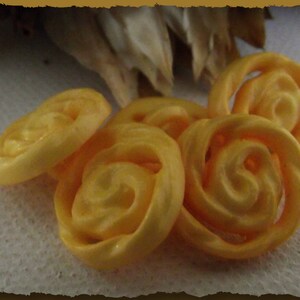 May include: Five yellow, swirl-shaped, crispy snacks on a white surface.