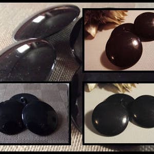 Puede incluir: Primer plano de una colección de botones negros brillantes de varias formas. Algunos son ovalados, otros redondos. Los botones tienen una superficie lisa y reflectante, lo que sugiere un material pulido. La imagen destaca los detalles de los botones.