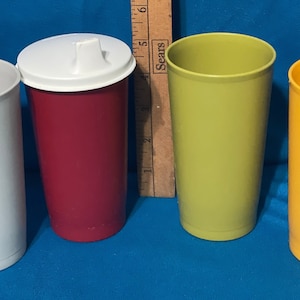 May include: Four plastic cups in different colors: white, red, green, and yellow. The cups are all the same size and shape.