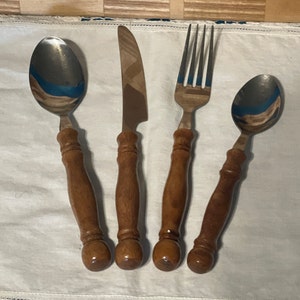 May include: A set of three silver utensils with wooden handles. The set includes a fork, a knife, and a spoon.