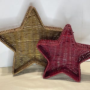 May include: Two star-shaped woven baskets. One is gold, the other is burgundy. The baskets are made of woven material and have a three-dimensional shape. They are likely decorative items.