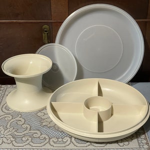 May include: A white plastic serving tray with four sections and a center well. The tray has a matching lid and a separate base.