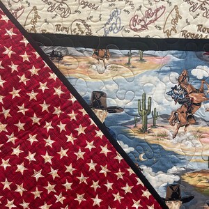 May include: A quilted fabric featuring a red section with a repeating pattern of beige stars and a black border separating it from a desert scene with cowboys on horseback, cacti, and mountains, plus a top section with Roy Rogers text.