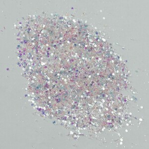 Puede incluir: Un mont&oacute;n de purpurina iridiscente con una mezcla de formas y tama&ntilde;os. La purpurina presenta una mezcla de tonos blancos, plateados, rosas, morados y azules. Las part&iacute;culas reflectantes brillan, creando un efecto brillante, ideal para manualidades y decoraciones.