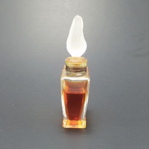 May include: A clear glass bottle with a pear-shaped stopper. The bottle is filled with a dark amber liquid.