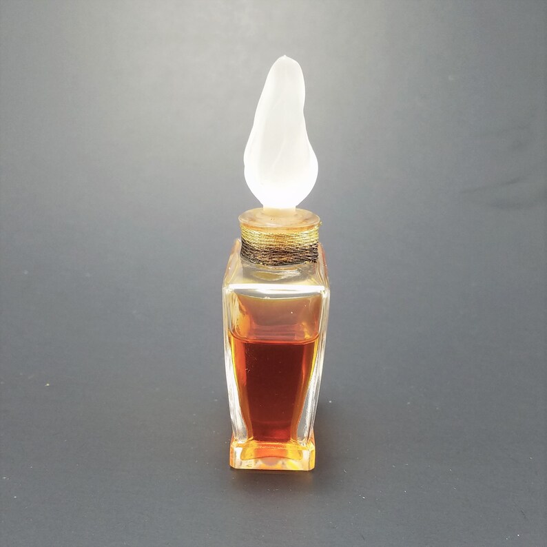 May include: A clear glass bottle with a pear-shaped stopper. The bottle is filled with a dark amber liquid.