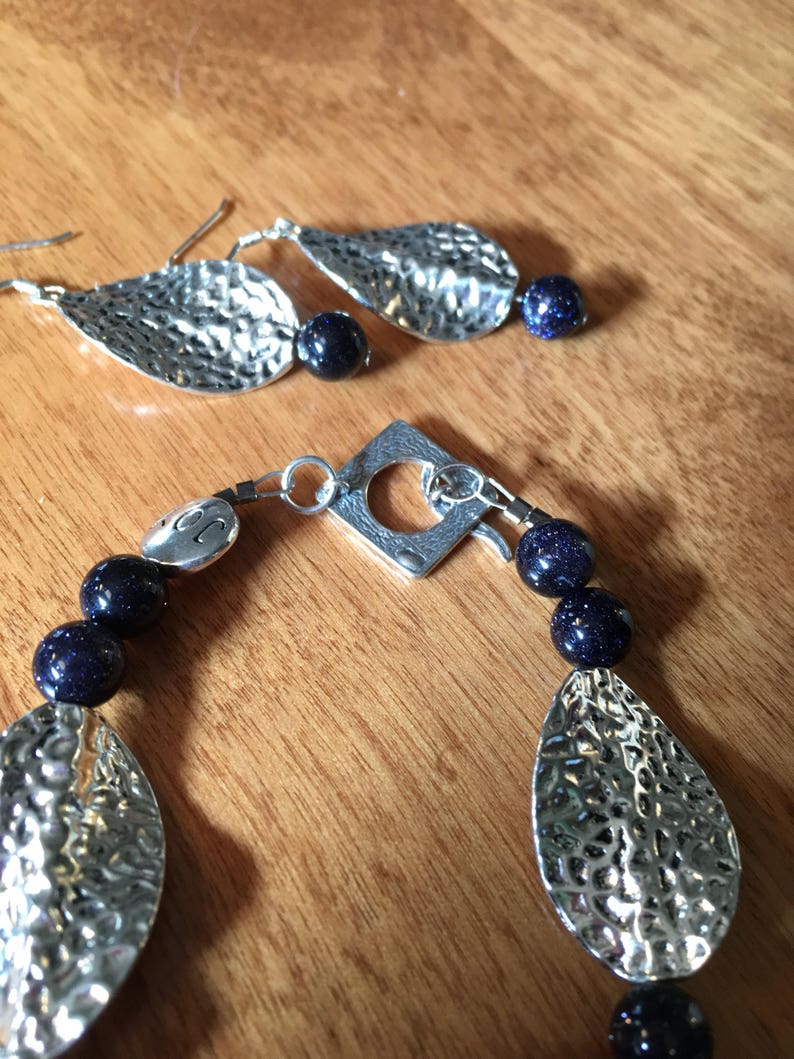 Unusual navy blue goldstone beads and pewter leaves on 7 bracelet amd earrings to match.