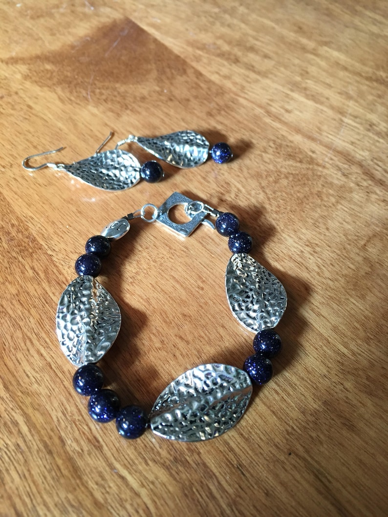 Unusual navy blue goldstone beads and pewter leaves on 7 bracelet amd earrings to match.